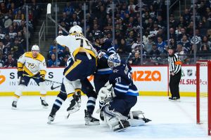 WINNIPEG, MB December 15: Winnipeg Jets goalie Connor Hellebuyck (37) makes a save despite a screen by Nashville Predators forward Juuso Parssinen (75) during the regular season game between the Winnipeg Jets and the Nashville Predators on December 15 2022 at the Canada Life Centre in Winnipeg MB. (Photo by Terrence Lee/Icon Sportswire via Getty Images)