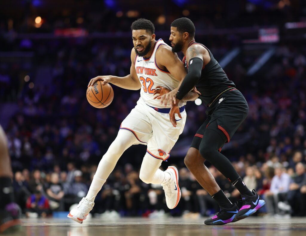 Jan 24, 2026; Philadelphia, Pennsylvania, USA; New York Knicks center Karl-Anthony Towns (32) drives against Philadelphia 76ers forward Paul George (8) during the first quarter at Xfinity Mobile Arena. Mandatory Credit: Bill Streicher-Imagn Images